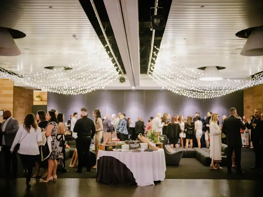 Guests socializing under fairy lights at wedding reception