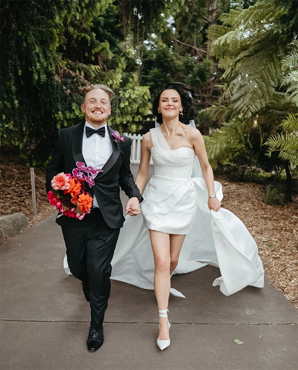 Bride and groom joyfully running with bouquet at Mount Annan Botanic Gardens