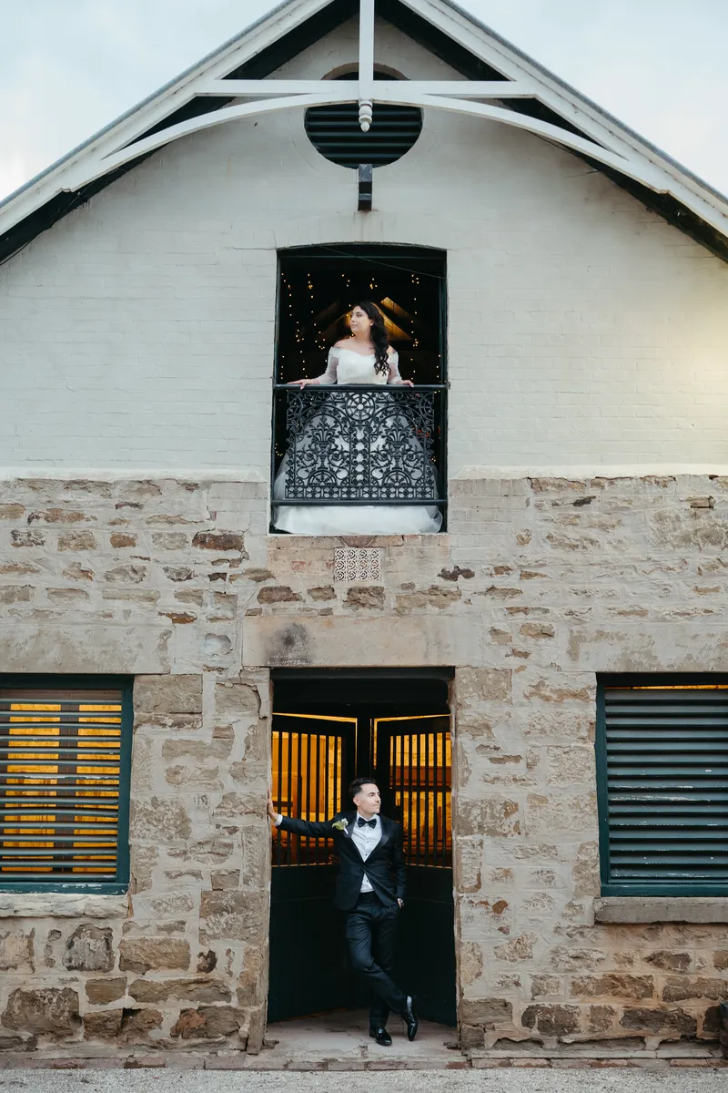 Bride on ornate balcony with groom below at Gledswood Homestead and Winery wedding venue
