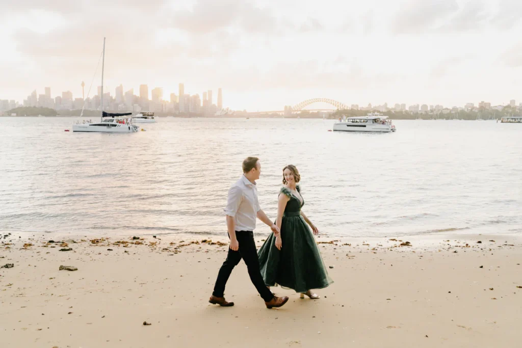 Couple walking on Athol Beach with Sydney Harbour Bridge and city skyline in the background