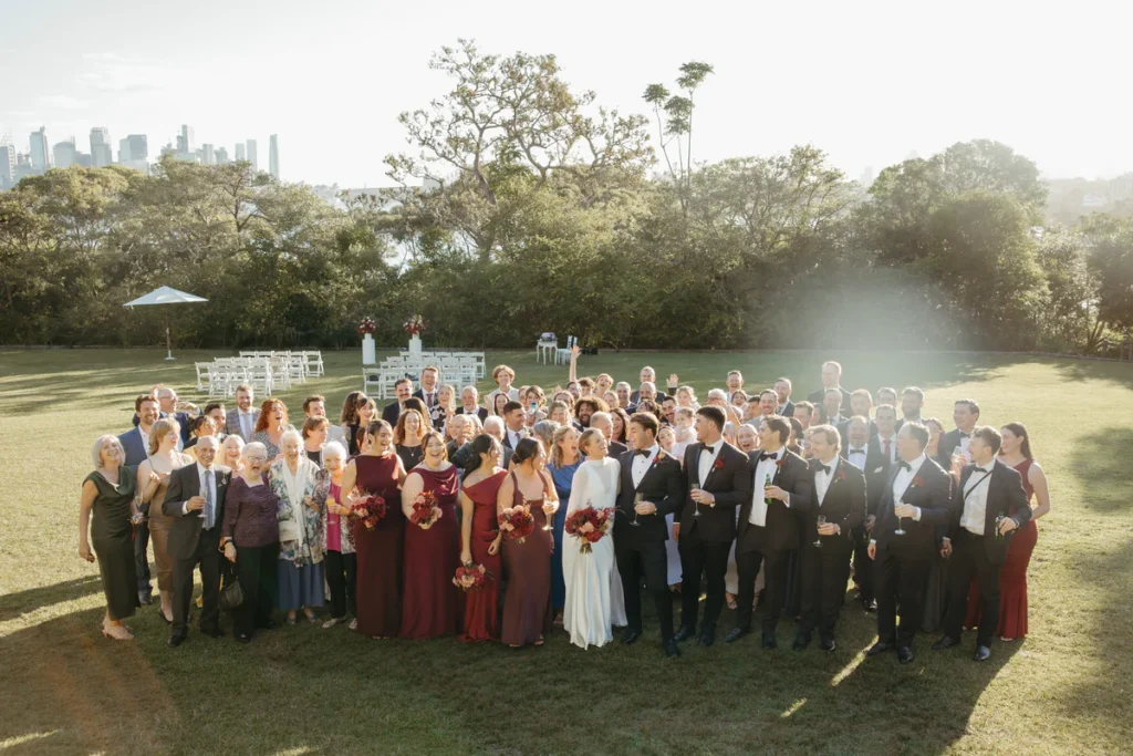 Wedding group photo on the lawn at Athol Hall Mosman with Sydney skyline in the background
