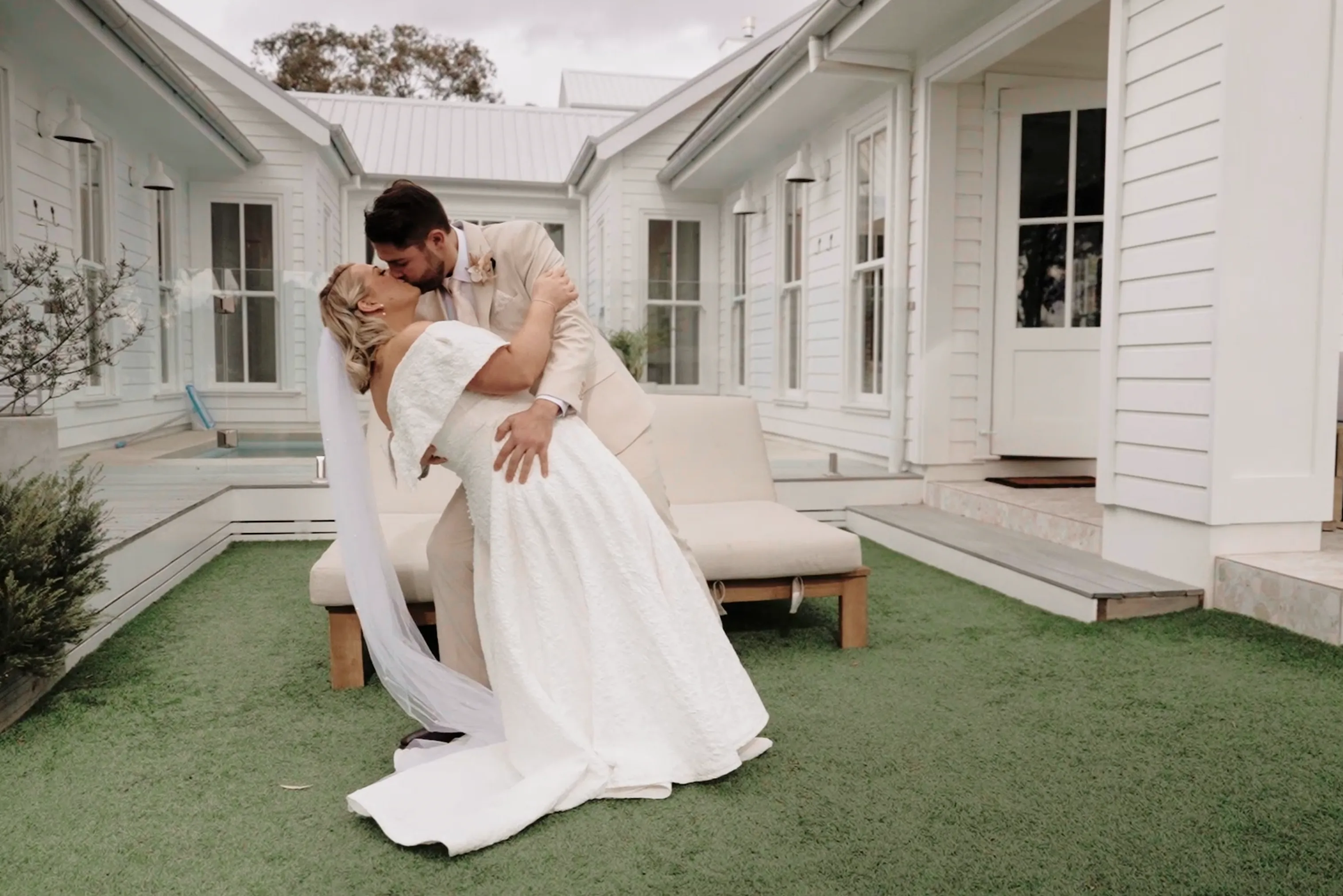 bride and groom kiss at white barn